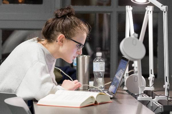 a person looking at a computer and textbook